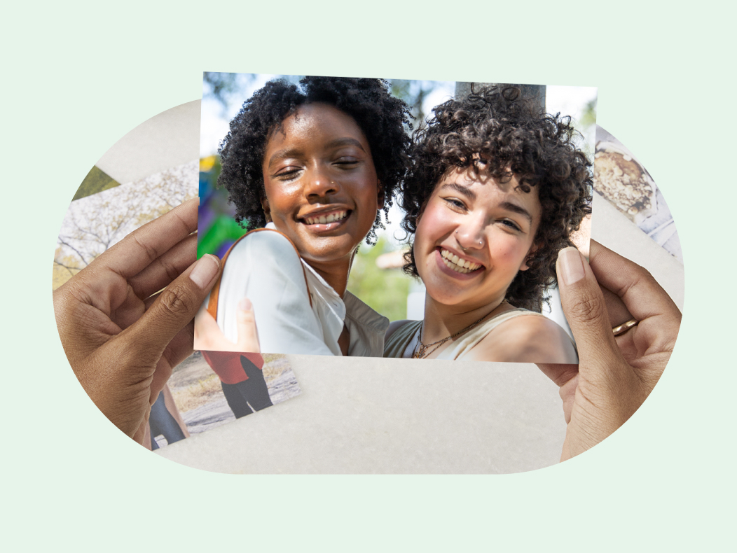 Hands hold a photo print of two women smiling.