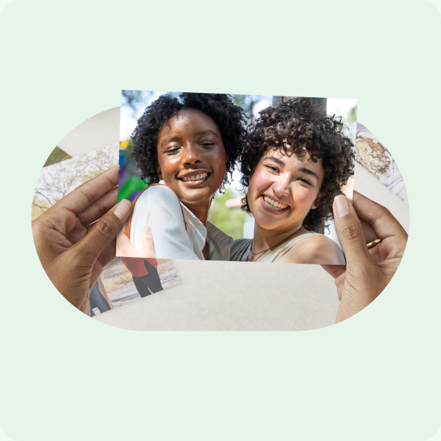 Hands hold a photo print of two women smiling.
