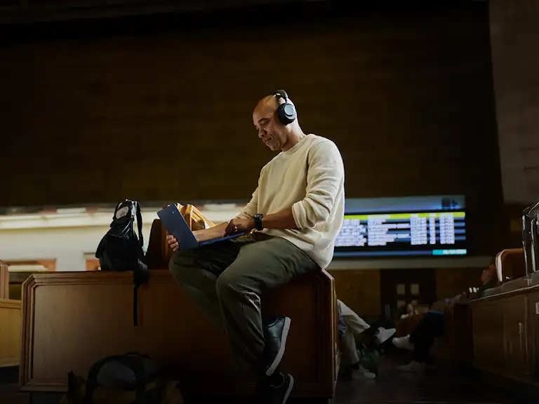 Image of a man using a Chromebook laptop and headphones whilst on the go.